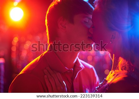 Romantic couple kissing on dance-floor in nightclub