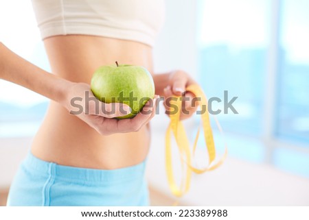 Slim and healthy female holding green apple in hand