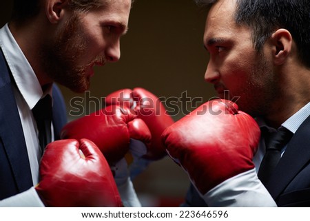Two furious businessmen in boxing gloves attacking one another