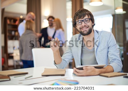 Modern businessman working in office on background of his partners interacting