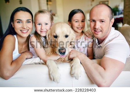 Friendly family members and their pet resting on sofa at home