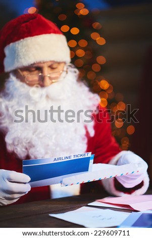 Santa Claus putting airline tickets into envelope