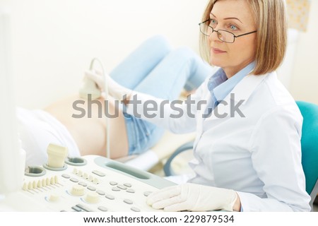Experienced obstetrician making an ultrasound examination to pregnant woman