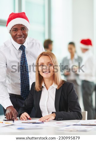 Caucasian and African-american co-workers looking at camera on background of their colleagues