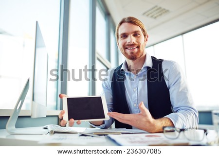 Cheerful young manager presenting new project in touchpad in office