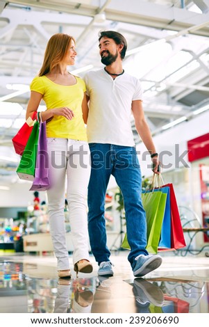 Amorous couple with paperbags buying presents in the mall