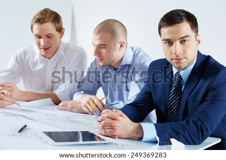 Serious young businessman looking at camera in working environment