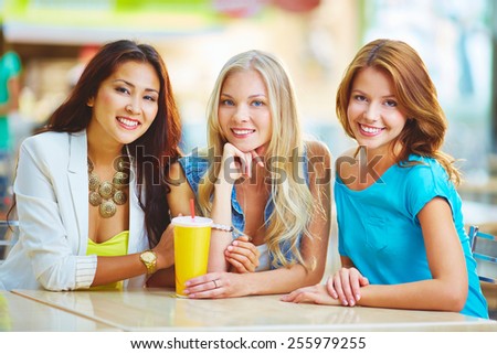 Three friendly girls having drink in cafe