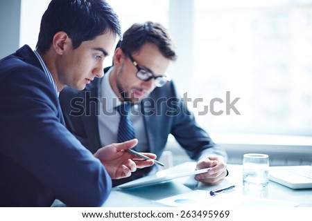 Serious businessman explaining data to his colleague at meeting