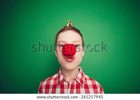 Funny boy with red clown nose looking at camera at foolÃ¢??s day celebration