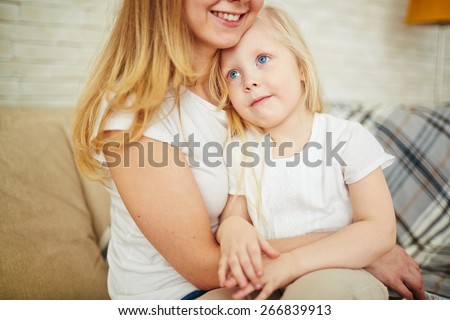 Calm girl sitting on the knees of her mother