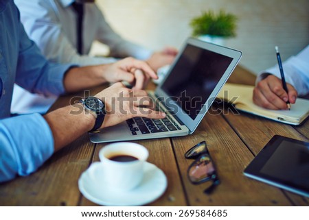 Male hands typing on laptop keypad in working environment