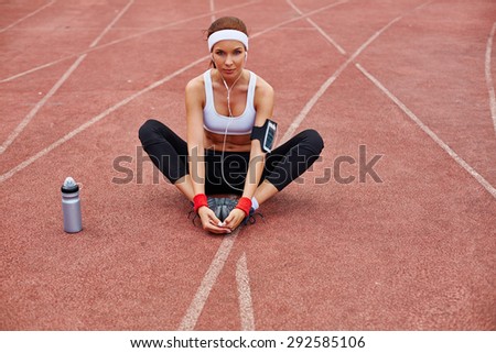 Young sporty woman in activewear sitting at stadium