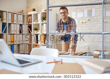 Pensive office worker looking at graph on transparent board