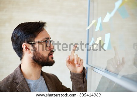 Attractive businessman pointing at notepaper on board