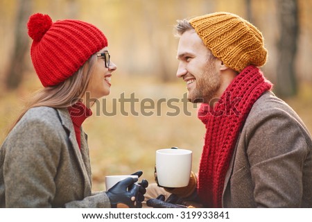 Joyful young couple talking outdoors while having tea