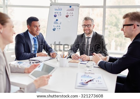 Group of confident co-workers consulting at meeting in office