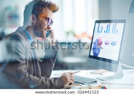 Businessman speaking on the phone in front of computer screen