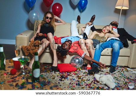 Messy room after wild house party, three tipsy stylish friends relaxing on couch while blond-haired woman with teddy bear posing for photography Foto d'archivio © 