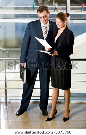 Businesswoman showing documents to her colleague in the building with glassy walls