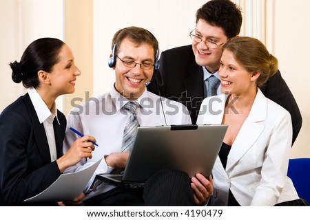 Team of four young business people gathered together around the laptop communicating with another department
