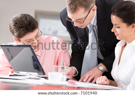 The serious boss is checking documents in presence of his colleagues