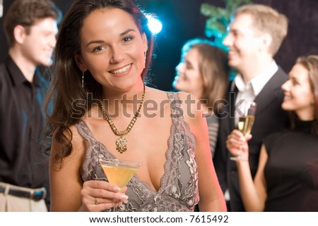 Portrait of charming woman holding her cocktail on the background of people
