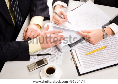 Horizontal image of two business people’s hands lying on the table with a cup of coffee and a cell near by