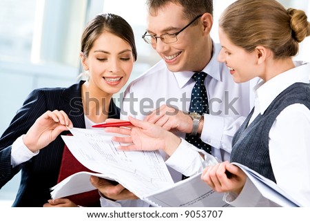 Image of three happy business people looking at business plan with smiles