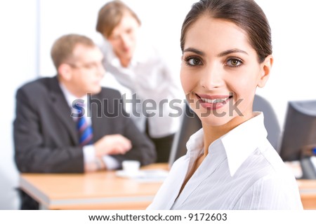 Face of beautiful employee with brown eyes on the background of her colleagues