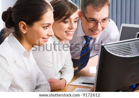 Team of three business people looking at the monitor and discussing some computer work