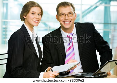 Two business people sitting at the table with a laptop on it in the office