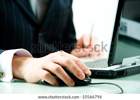 Image of male hand touching a computer mouse with laptop near by