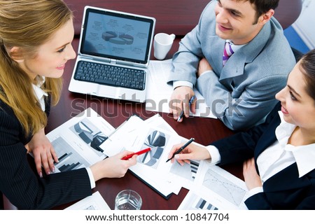 Image of business woman explaining and pointing to her project to colleagues
