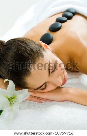 Image of a pretty girl lying in the beauty salon with closed eyes and enjoying spa procedure with madonna lily by her head