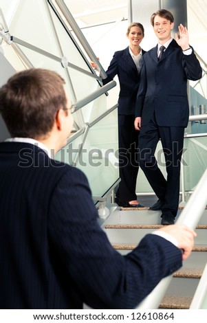 Portrait of business people looking each other and greeting at stairs in the office building