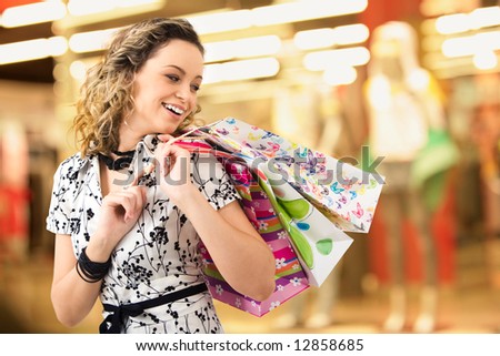 Photo of young joyful woman with shopping bags on the background of shop windows