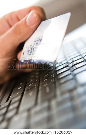 Close-up of human hand holding plastic card over black keyboard