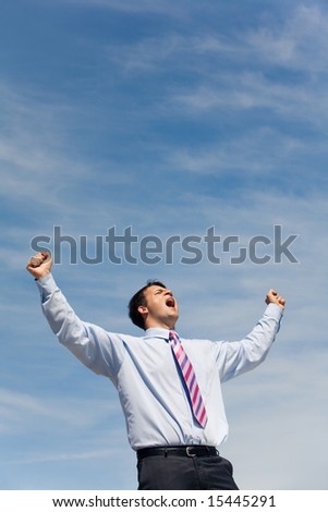 Portrait of young happy man with his arms raised up to the sky and screaming