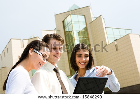 Portrait of group of people looking at laptop monitor during corporate work outside