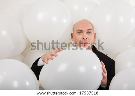 Photo of attractive male holding big white balloon in hands and looking at camera