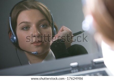 Reflection of face of female with headset holding pen in hand