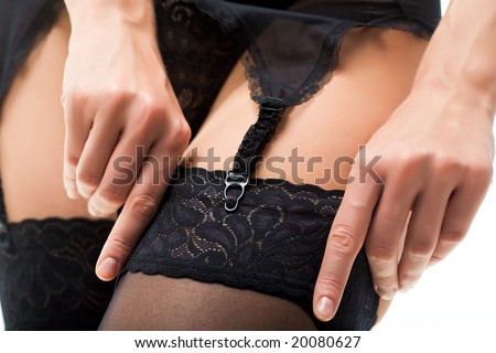 Close-up of female?s hand putting on black stocking and fastening garter belt