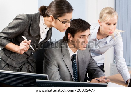 Three colleagues gazing at monitor with serious expressions during meeting