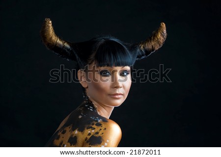 Portrait of serious woman with hairstyle in form of horns looking at camera over black background