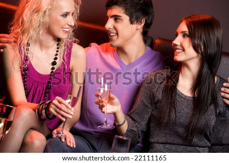 Portrait of smart young people holding champagne flutes and chatting with each other