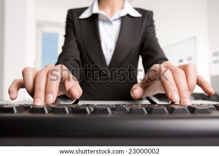 Close-up of businesswoman in black suit typing a letter