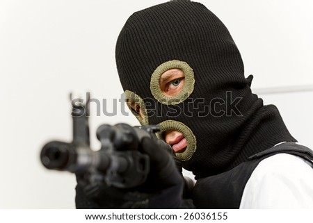 Head of murderer in balaclava pointing his gun at camera and looking into it