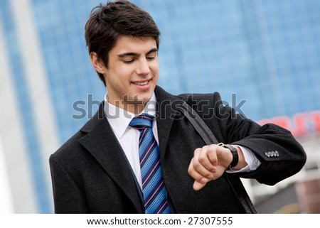 Photo of busy young man watching the time and smiling