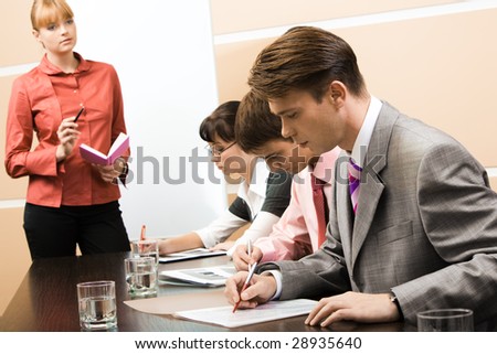 Image of executive managers learning documents with business leader standing near by